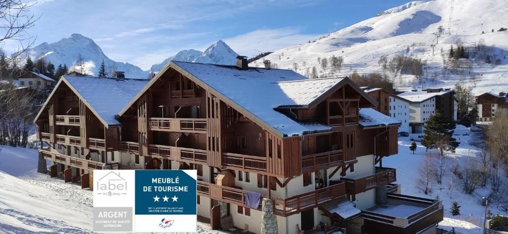 莱德萨阿尔卑斯T2 Meublé Tourisme 3 etoiles, pied des pistes-parking privé avec balcon et superbe vue的雪中一座建筑物,前面有标志