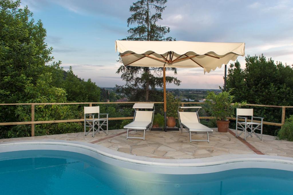 圣朱利亚诺-泰尔梅Villa Alta - Residenza d'epoca con piscina的一个带遮阳伞和椅子的庭院和一个游泳池