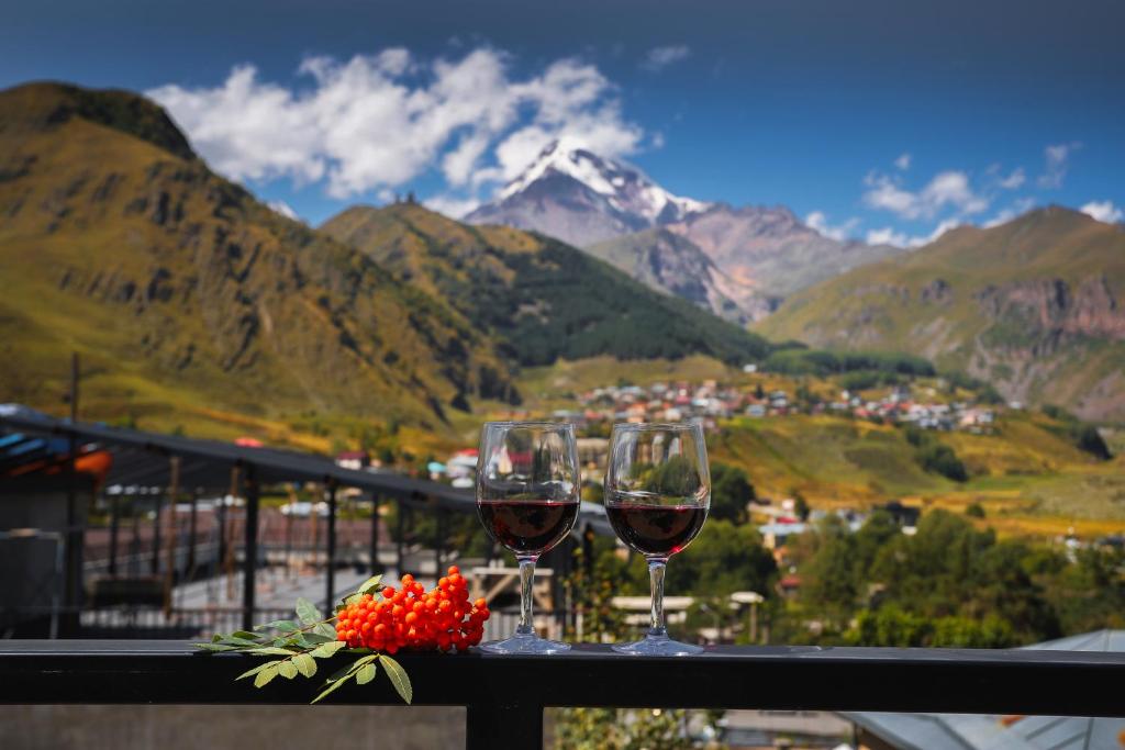 卡兹贝吉Hotel INSIDE Kazbegi的一张桌子上放两杯葡萄酒,享有山景