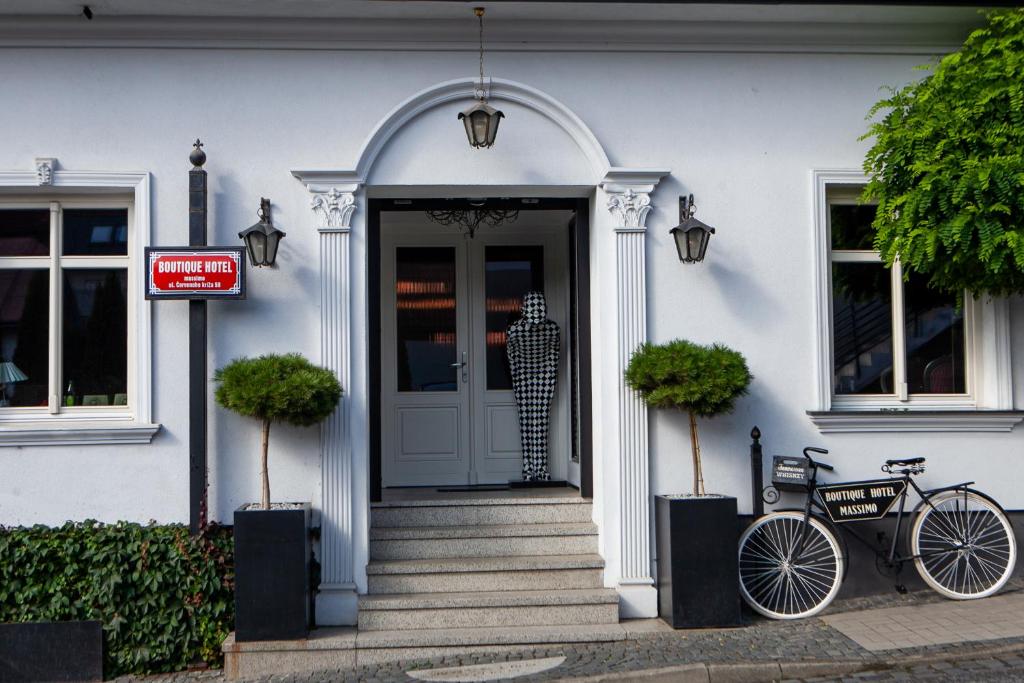 纳梅斯托沃Boutique Hotel Massimos的停在白色房子前面的自行车