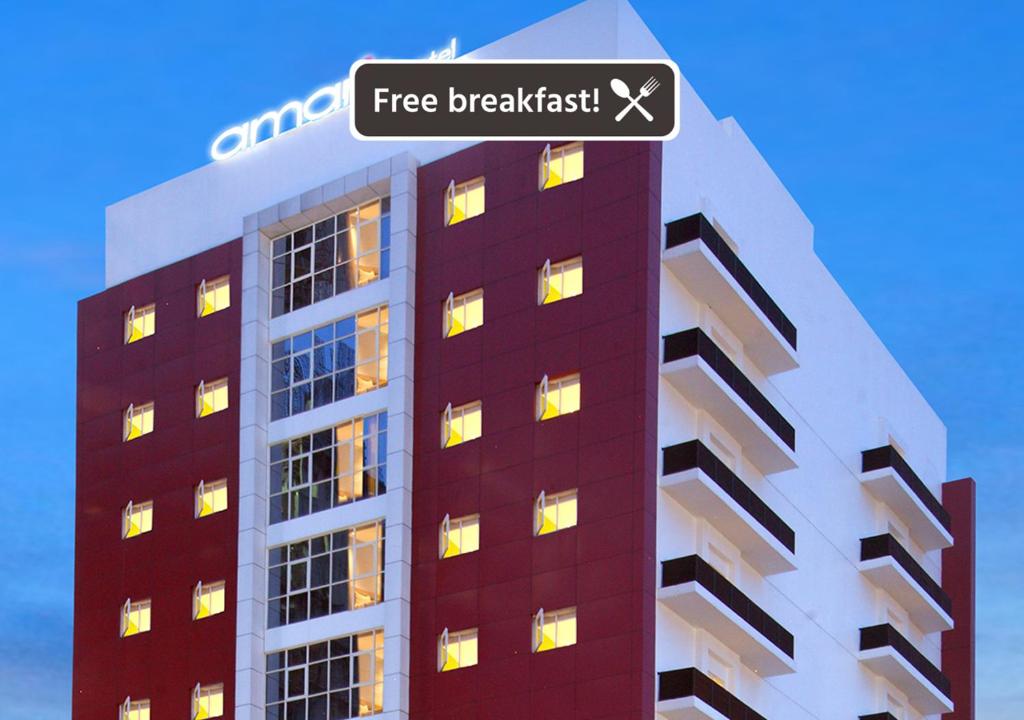 泗水爱玛瑞丝泗水马格雷酒店的一座高大的建筑,上面标有阅读免费早餐的标志