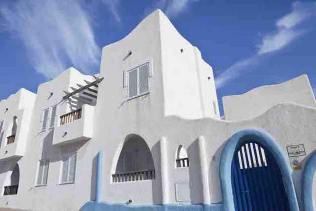 拉伊斯莱塔德尔摩洛Apartamento a 2 minutos andando a la playa.的前面有蓝色物体的白色建筑