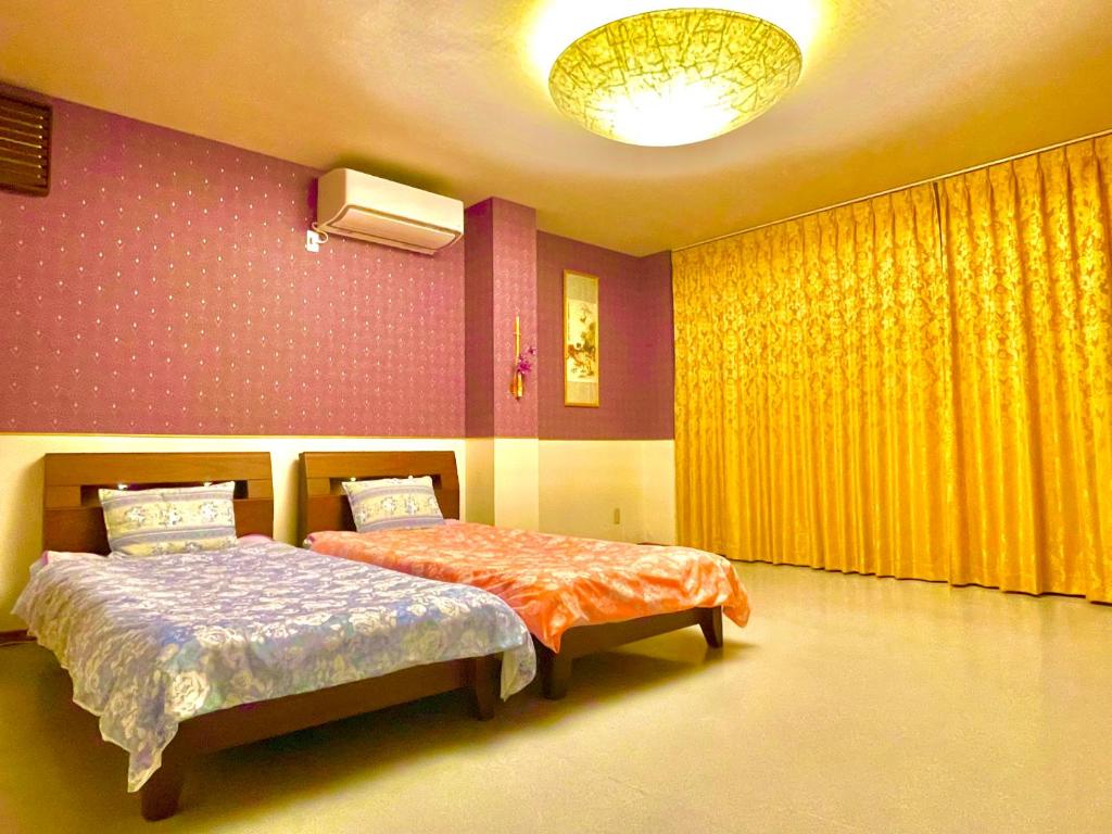 犬山市犬山モダンルーム的一间卧室设有两张床和黄色窗帘