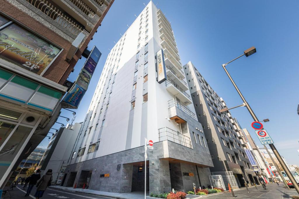 东京Super Hotel Tokyo Akabane Eki Minamiguchi的街道拐角处高大的白色建筑