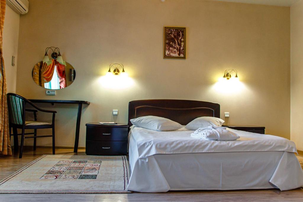 新库兹涅茨克Boutique hotel Persona的一间卧室配有一张带两个枕头和一张桌子的床。