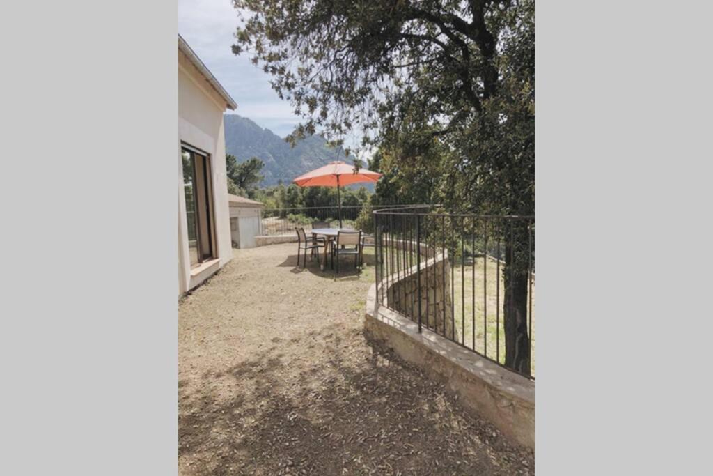 SocciaVilla familiale entre mer et montagne Corse的一个带桌子和遮阳伞的庭院