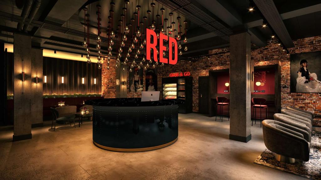 克劳利Radisson RED London Gatwick Airport的一间设有酒吧的餐厅,酒吧上标有红色 ⁇ 虹灯