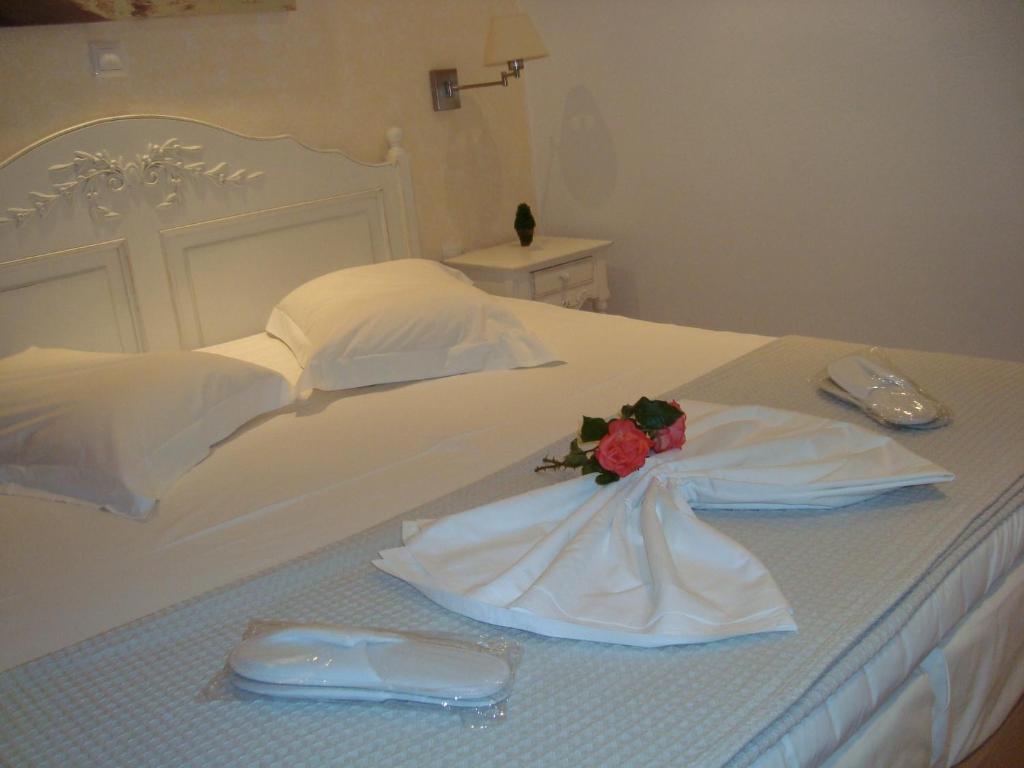 阿斯提帕莱亚镇Stampalia Luxury Studios的一张白色的床,上面有连衣裙和花