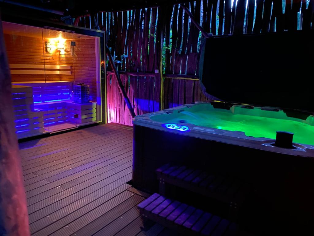 沙托劳尔尧乌伊海伊BNCK Wellness Residence的配有带绿色和紫色灯的浴缸的客房