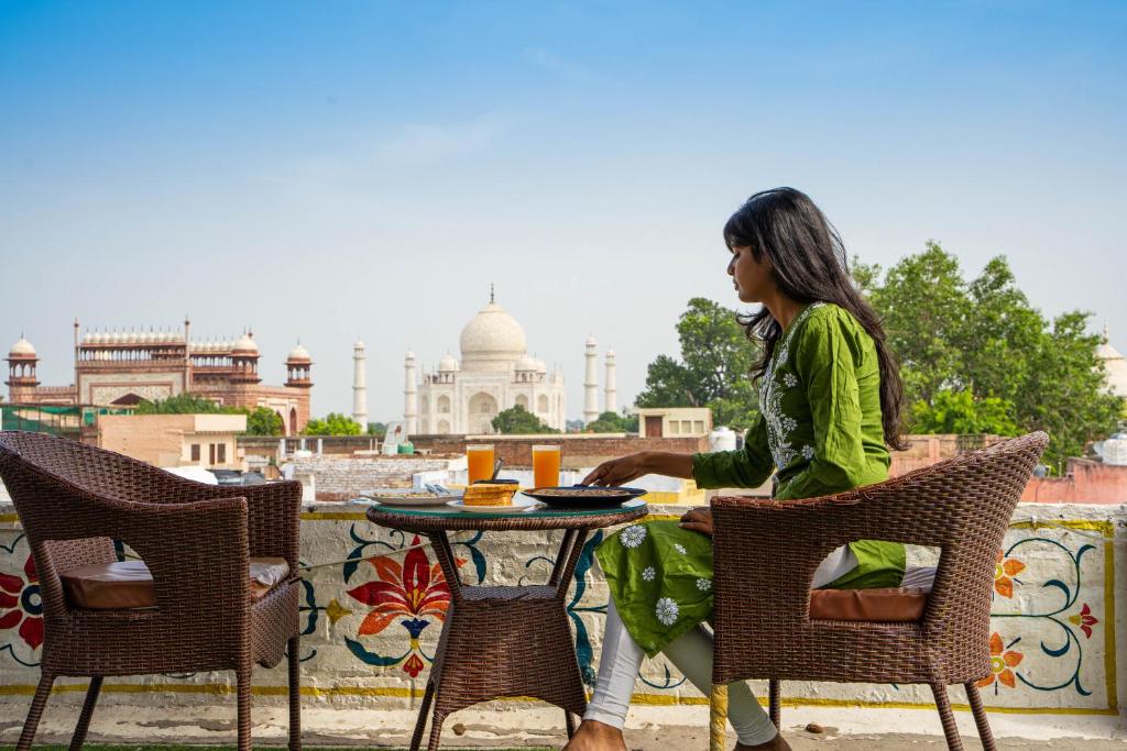 阿格拉Joey's Hostel Agra的坐在大楼前桌边的女人
