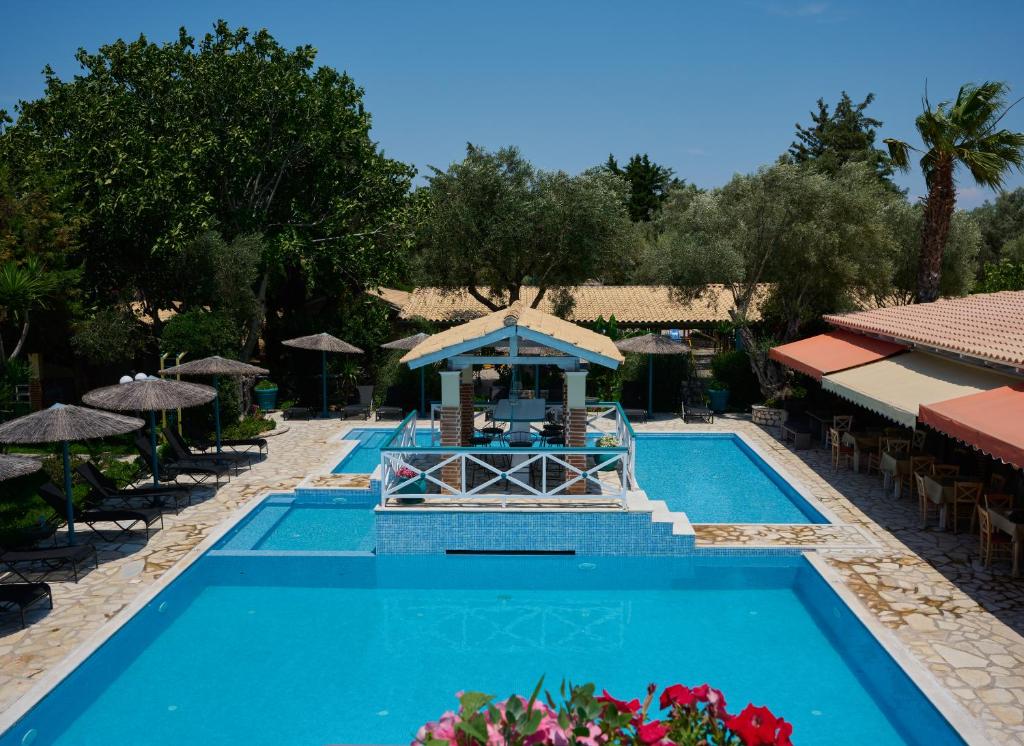 雷夫卡达镇Villaggio Maistro的度假村的游泳池配有桌子和遮阳伞