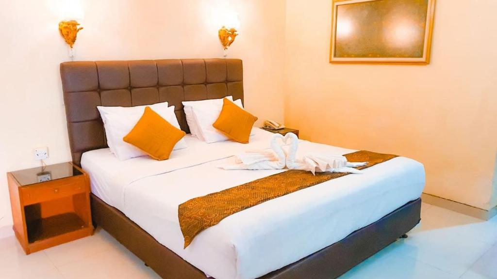 梭罗Mandala Wisata Hotel的一间卧室配有一张大床,提供黄色和橙色枕头