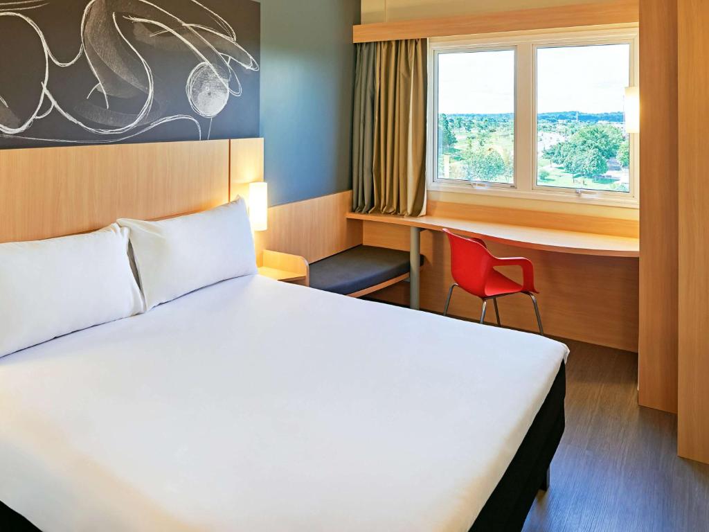 里约布兰科ibis Rio Branco的配有一张床、一张书桌和一扇窗户的酒店客房