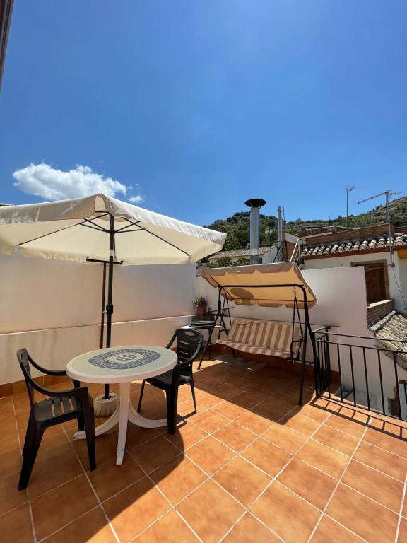 莫纳奇尔Casa rural Los Abuelos的屋顶上带桌子和遮阳伞的庭院