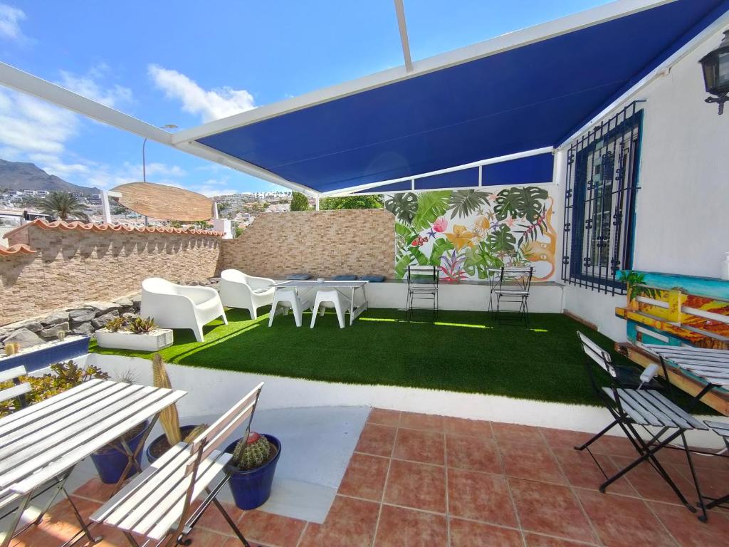 阿德耶Endless Summer House的庭院配有白色椅子和蓝色遮阳伞