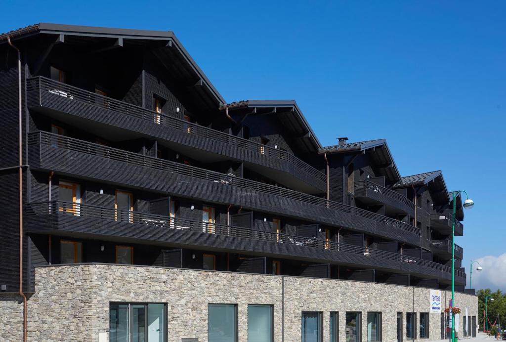 莱德萨阿尔卑斯Résidence Néméa Le Hameau - Les Deux Alpes的一座黑色建筑,旁边设有阳台