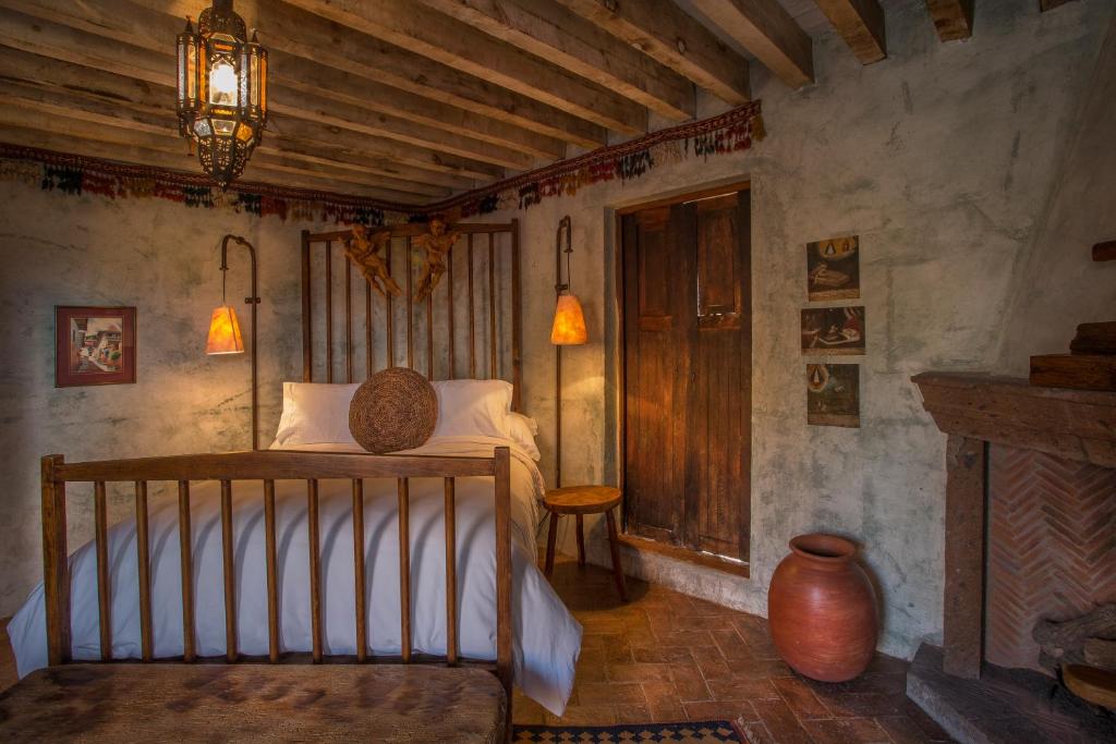 圣米格尔-德阿连德Hacienda Las Amantes的带壁炉的客房内的一间卧室配有一张床