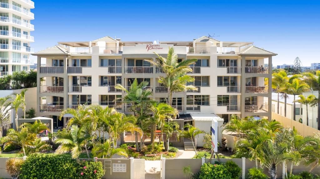 玛志洛太平洋天堂公寓酒店的一座白色的大建筑,前面有棕榈树