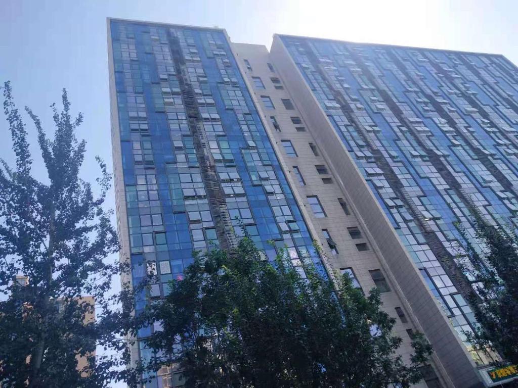 北京Chaoyang Joy City Hardcover Apartment的一座高高的建筑,上面有蓝色的玻璃窗
