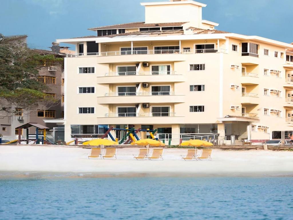 弗洛里亚诺波利斯Hotel Monteiro Canasvieiras的海滩上的酒店,配有椅子和遮阳伞