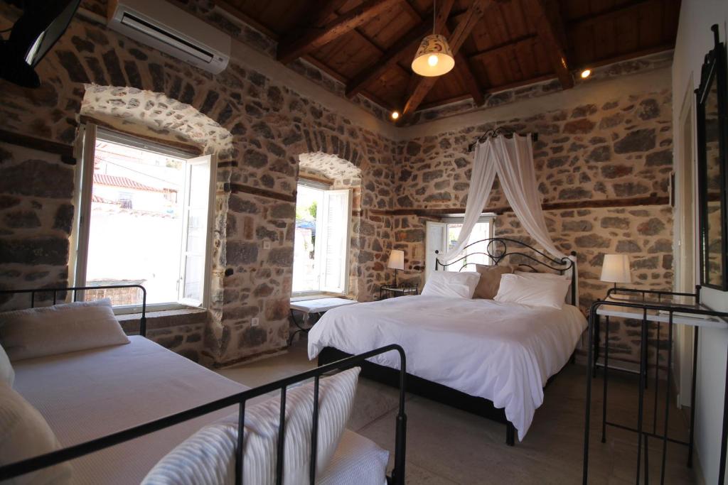 伊兹拉亚历山德拉旅馆的一间带两张床铺的卧室,位于带石墙的房间内