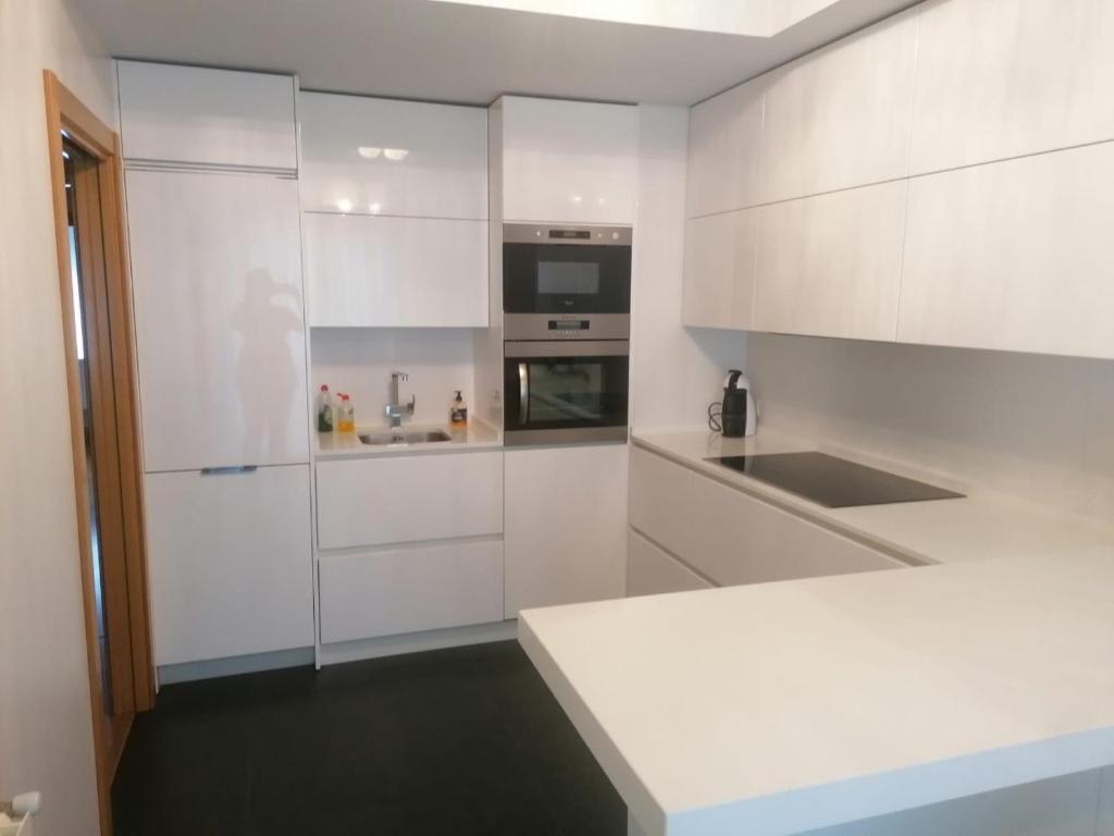 维多利亚-加斯特伊兹Apartamento Praga的白色的厨房配有白色橱柜和水槽