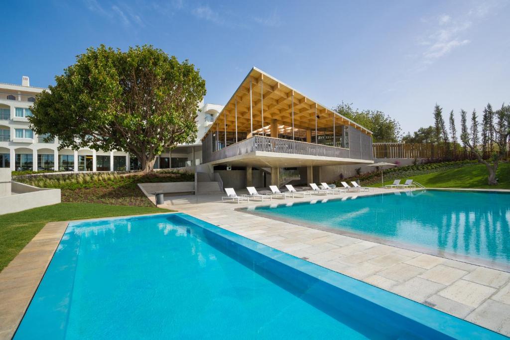 塔维拉OZADI塔维拉酒店 的一座带建筑物的房子前的游泳池