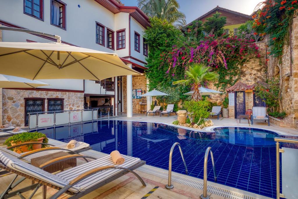 安塔利亚多安酒店的房屋旁的游泳池配有椅子和遮阳伞