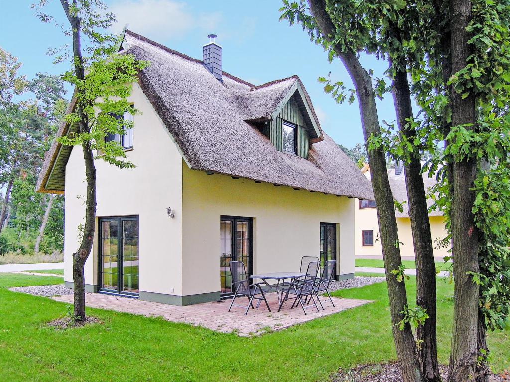 ZirchowReetdachhaus mit Sauna, Kamin & Terrasse - D 028.032的白色的房子,设有茅草屋顶,配有桌椅