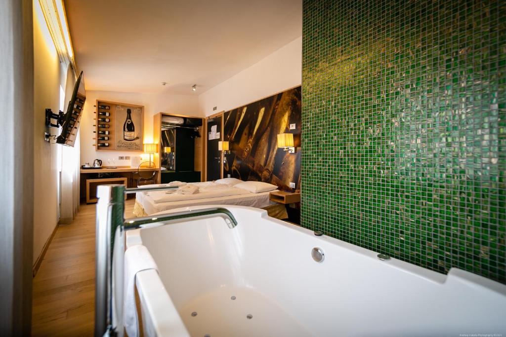 特伦托Boutique Exclusive B&B的带浴缸的浴室和绿色瓷砖墙