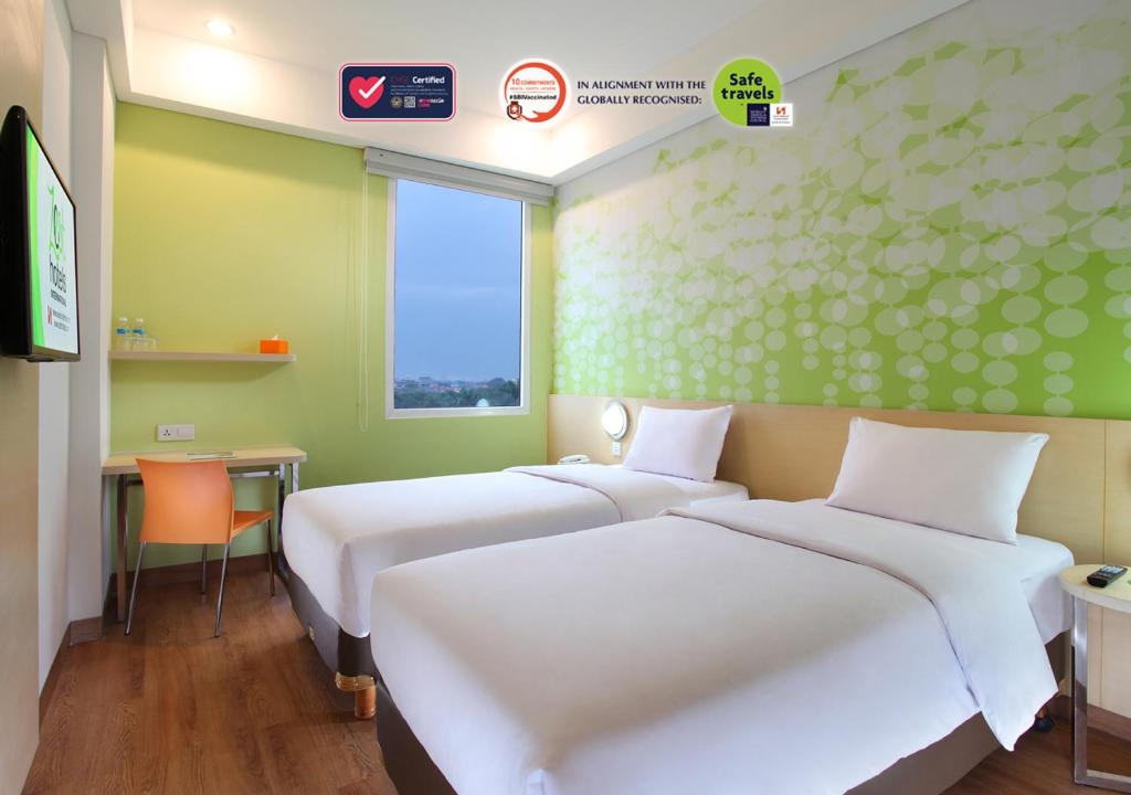 当格浪Zest Airport Jakarta by Swiss-Belhotel International的配有两张床铺、绿色墙壁和电视的客房