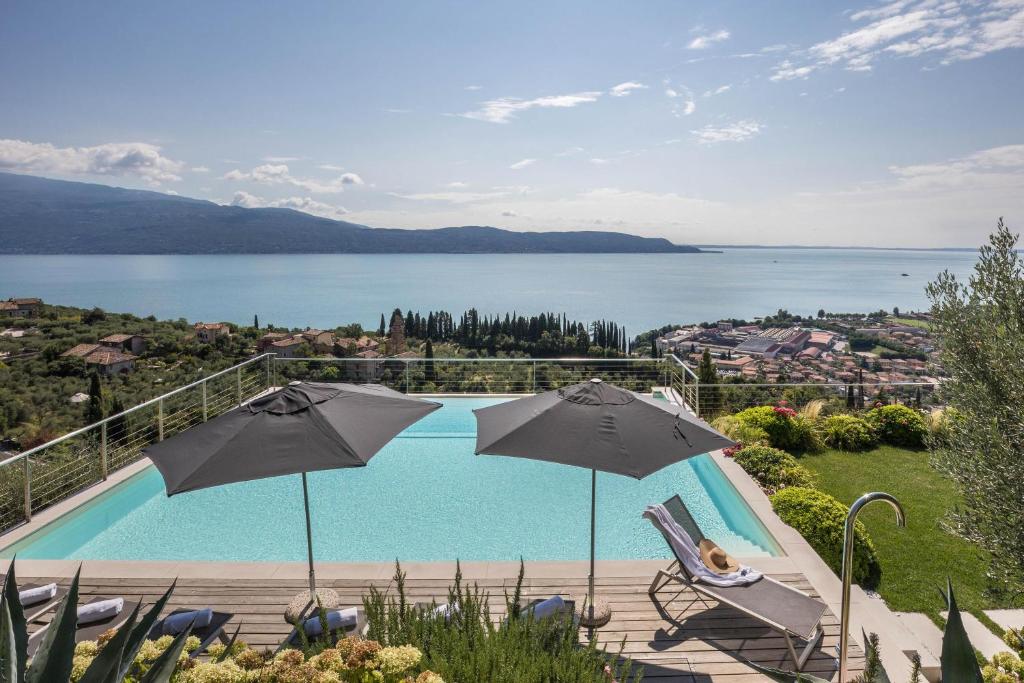 托斯科拉诺-马德尔诺Exclusive Villa Agave的一个带两把遮阳伞的游泳池,享有水景