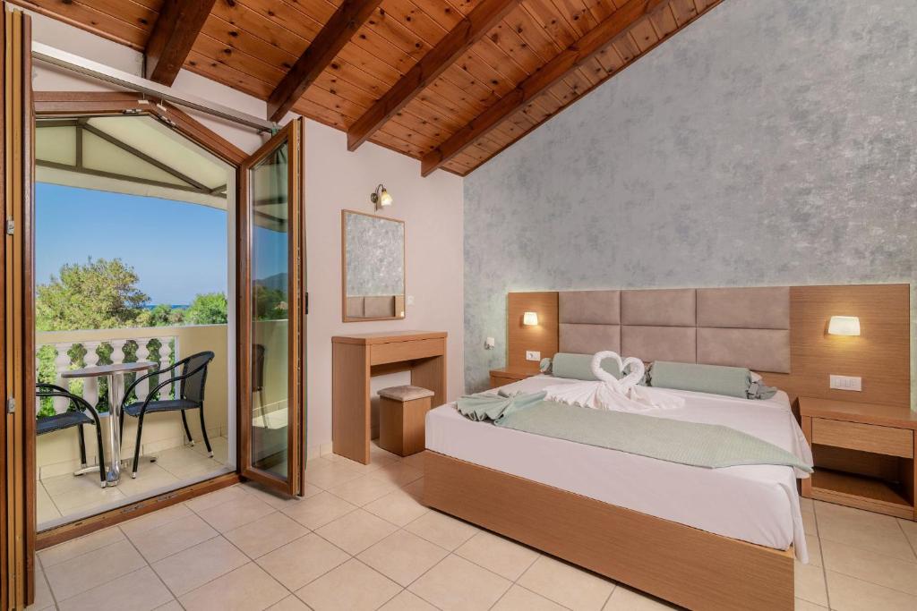 瓦西里科斯普拉卡海滩度假酒店的一间卧室配有一张床,阳台配有桌子