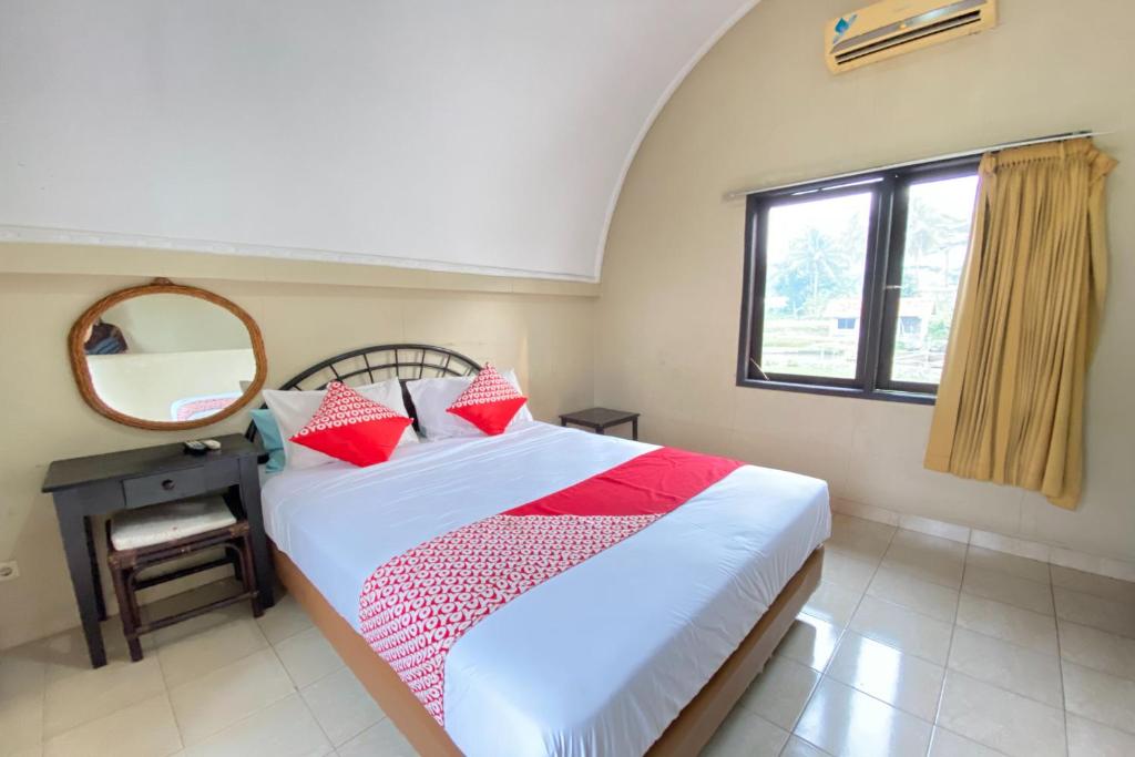 梳邦再也SUPER OYO Flagship 90644 Cottage Nalendra Nuansa Nusantara的一间卧室配有一张带红色枕头和镜子的床