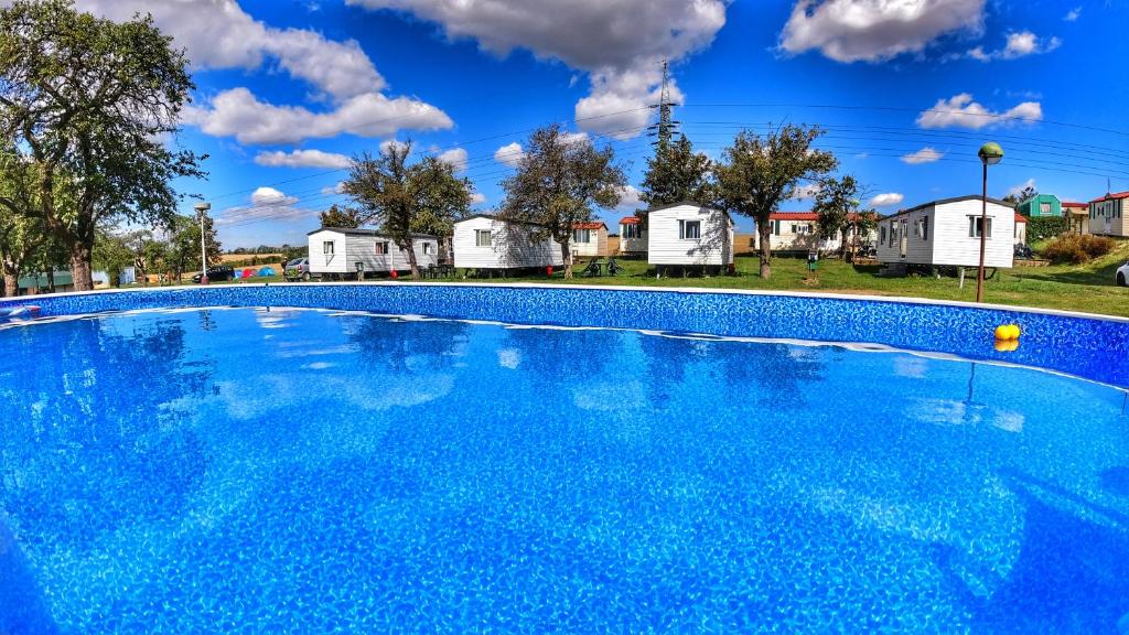 布拉格Triocamp Praha的一座大型蓝色游泳池,其背景是房屋