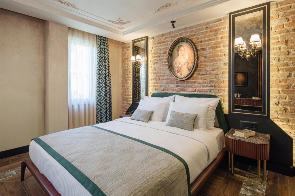 伊斯坦布尔伊斯坦布尔特里亚酒店的一间卧室设有一张大床和砖墙