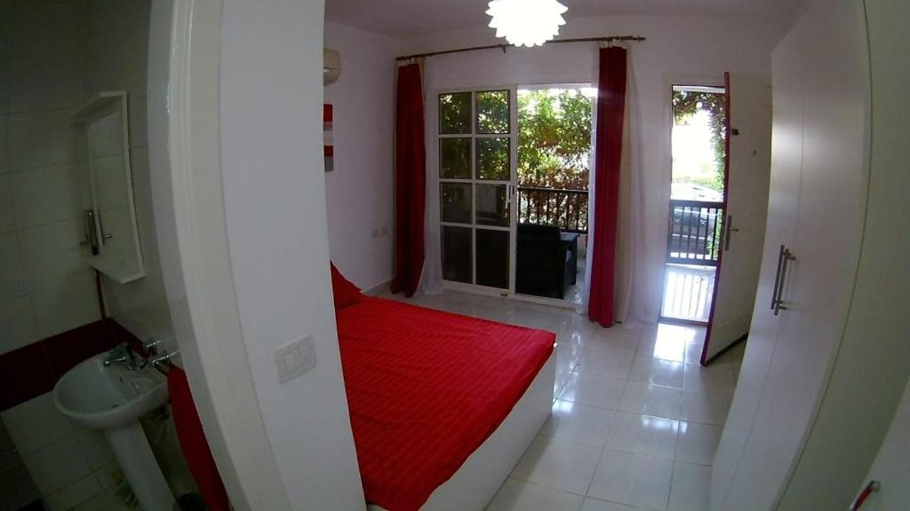沙姆沙伊赫Delta Sharm Holiday的带红色床的客房,浴室设有窗户