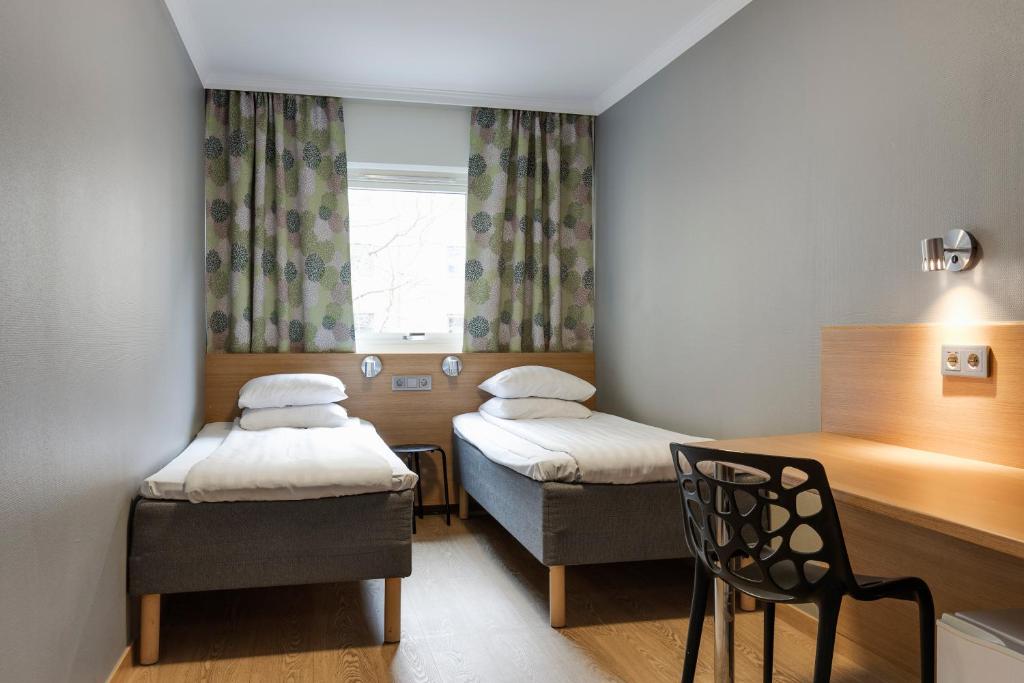 哥德堡哥德堡迷你酒店的客房设有两张床、一把椅子和窗户。