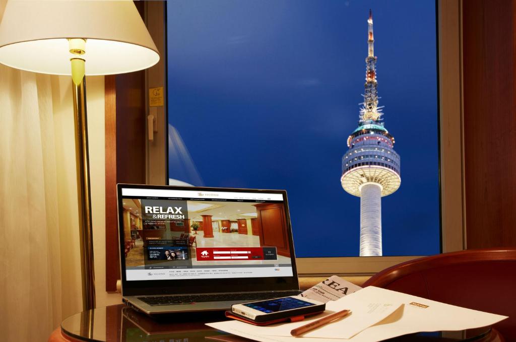 首尔首尔明洞世宗酒店的一台笔记本电脑坐在桌子上,享有电视塔的景色