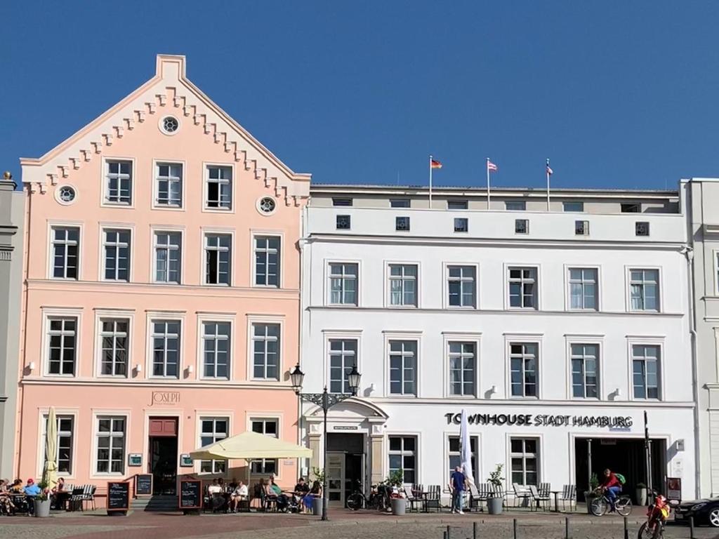 维斯马Townhouse Stadt Hamburg Wismar的一座白色的大建筑,外面的人坐在