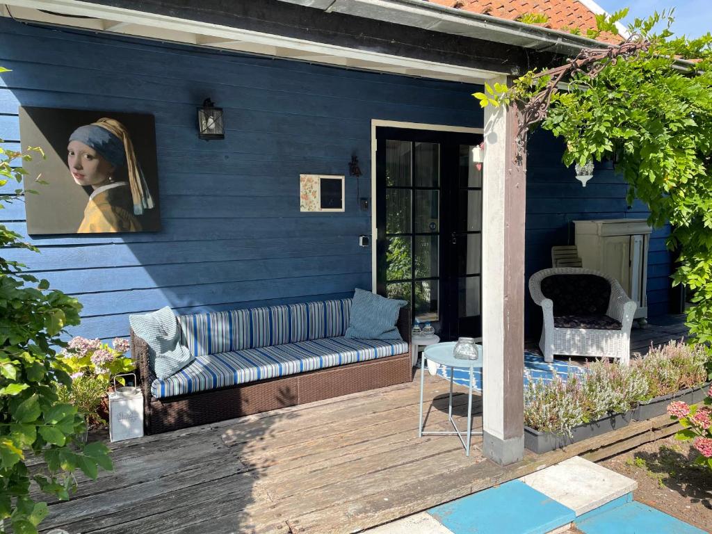 瓦尔德Bed en breakfast Onder aan de dijk的蓝色的房子,在木甲板上配有沙发