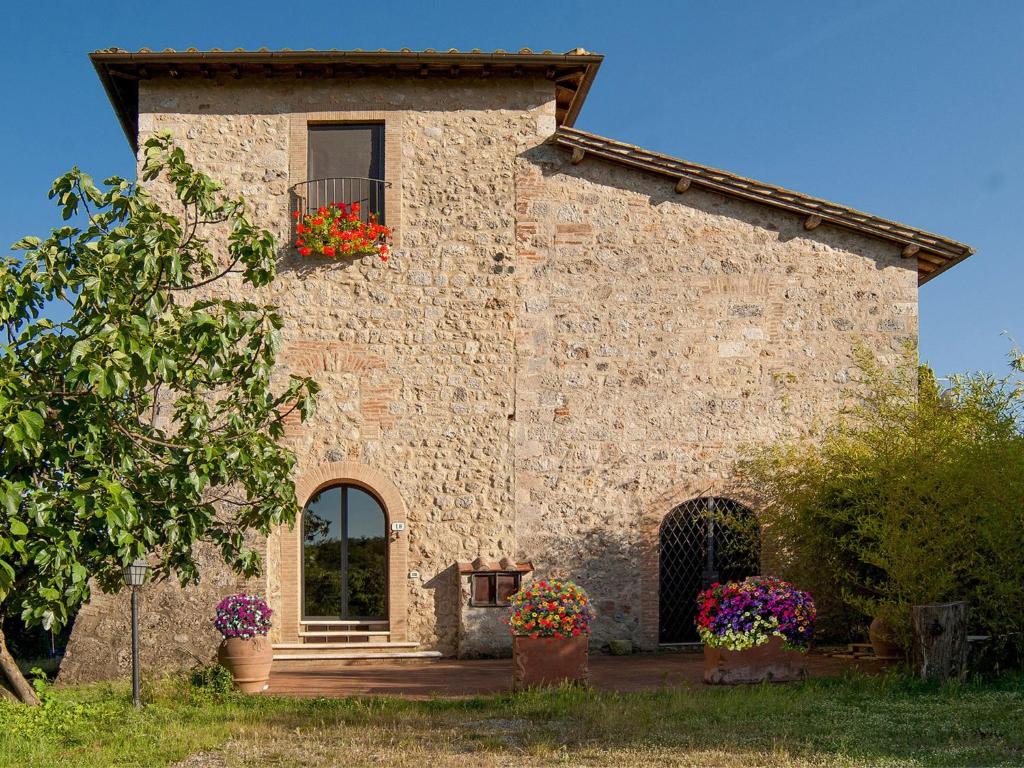 蒙特里久尼Torre Della Chiocciola的一座石头建筑,上面有窗户和花盒