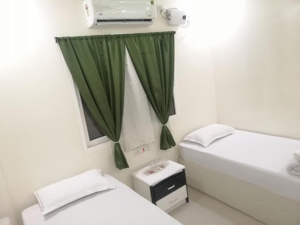 菩提伽耶RAJHAT MARANAO House的浴室设有两张床和绿帘。