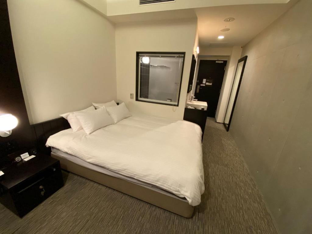 富良野ＦＵＲＡＮＯ ＮＡＴＵＬＵＸ ＨＯＴＥＬ - Vacation STAY 68187v的一间卧室配有带白色床单和枕头的床。