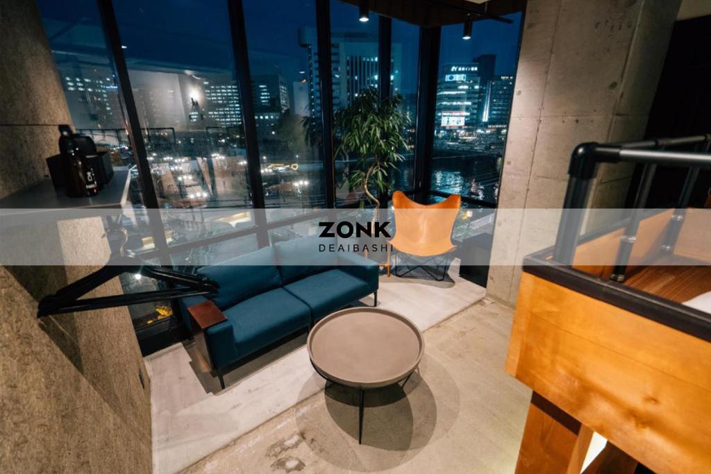 福冈ZONK HOTEL Nakasu-Deaibashi的一间配有沙发、桌子和窗户的客房