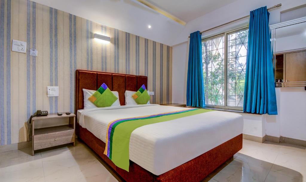 浦那Treebo Trend Iris Suites的一间卧室配有一张带蓝色窗帘的大床