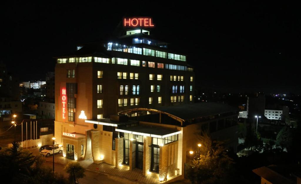 希伯仑Regency Hotel Hebron的一家晚上在上面标有标志的酒店