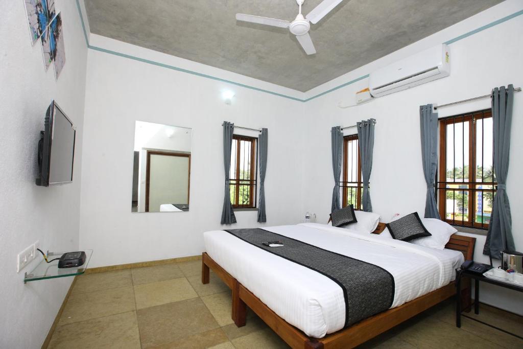 蓬蒂切里Hotel Du Palais - Auroville Beach的卧室设有白色大床和窗户。