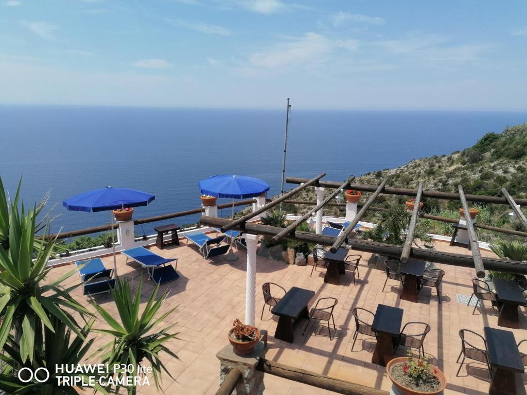 伊斯基亚Hotel Punto Azzurro的一个带椅子和遮阳伞的庭院和大海