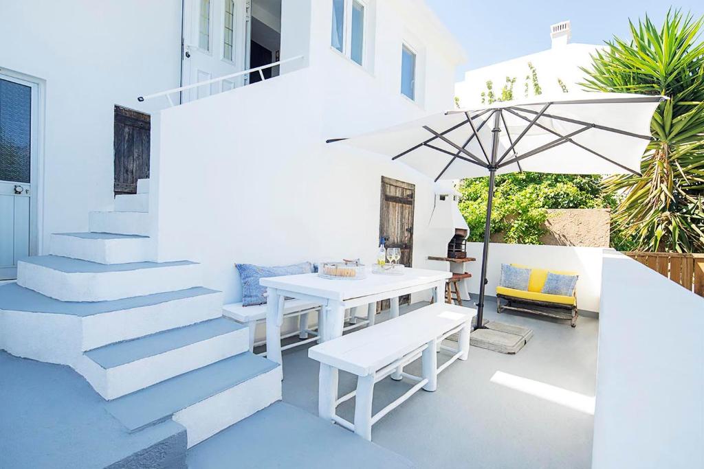 塞勒玛Casa Cavala by Sevencollection的白色的庭院配有桌子和遮阳伞。